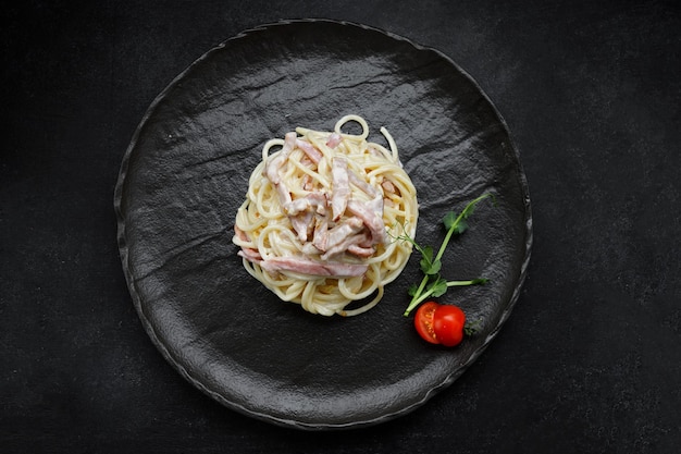 Pasta alla carbonara con pomodori su un piatto nero