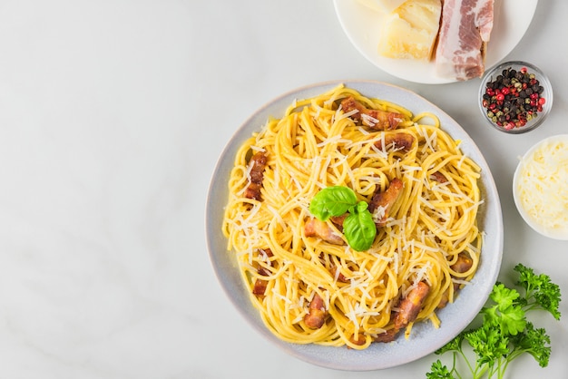 Pasta alla carbonara, spaghetti con pancetta, uovo, parmigiano duro e basilico in un piatto. Cucina italiana tradizionale