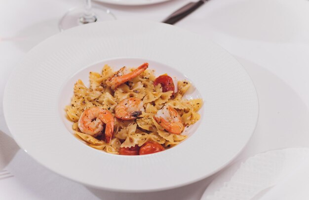 Pasta bavette con gamberi fritti bechamel salsa di menta foglia di aglio pomodori chili su piatto bianco vista dall'alto cucina italiana