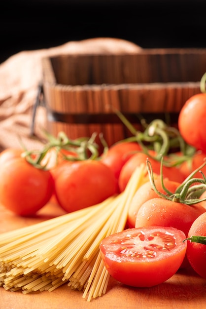 Pasta bellissimi dettagli di pomodori rossi e fili di spaghetti crudi su legno rustico fuoco selettivo