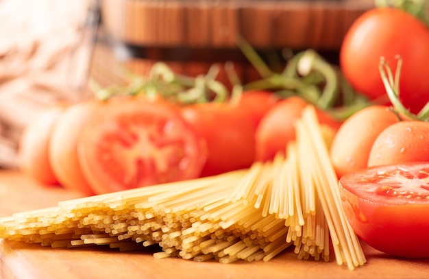 Pasta bellissimi dettagli di pomodori rossi e fili di spaghetti crudi su legno rustico fuoco selettivo