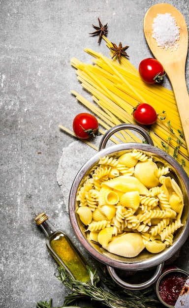 Pasta bollita in padella con olio e pomodorini. Sul tavolo di pietra. Vista dall'alto