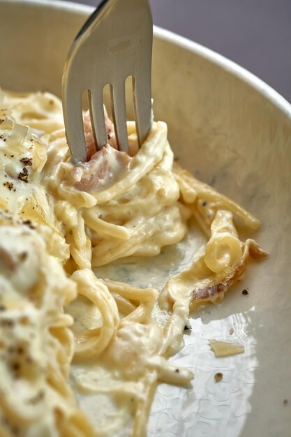 Pasta carbonara con crema e formaggio in un piatto