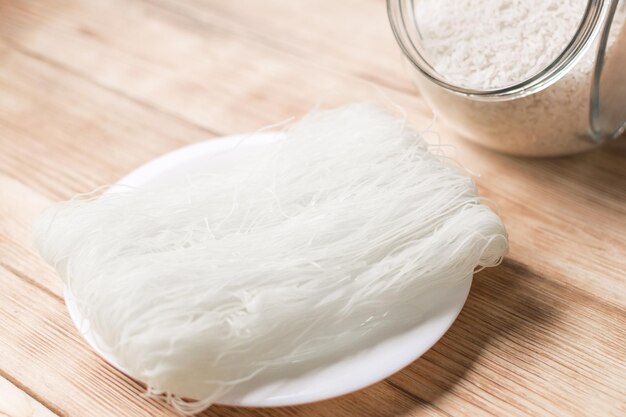 Pasta cinese di spaghetti di riso secco su un fondo di legno