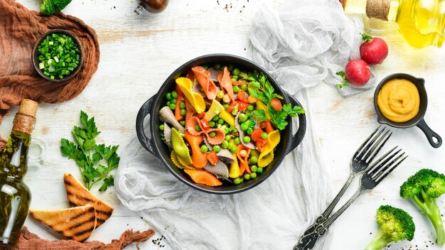 Pasta colorata con piselli e verdure in una ciotola nera Vista dall'alto Spazio libero per il testo