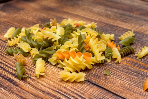 Pasta colorata, spaghetti colorati, maccheroni, pasta su fondo di legno