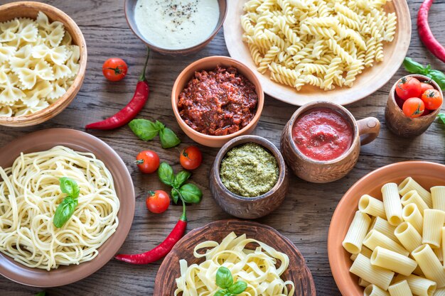 Pasta con diversi tipi di salsa sul tavolo di legno