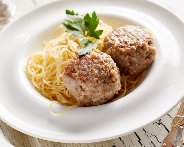 Pasta con due cotolette sul tavolo bianco rustico