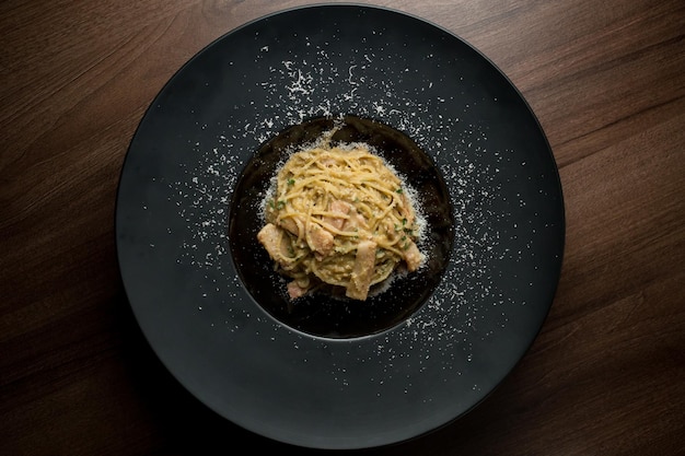 Pasta con fette di prosciutto parmigiano alle erbe e uovo su un piatto nero su fondo di legno