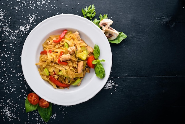 Pasta con filetto di pollo parmigiano e funghi e basilico Su una superficie di legno nera Spazio libero per il testo Vista dall'alto