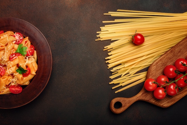 Pasta con formaggio e pomodoro ciliegia su fondo arrugginito.