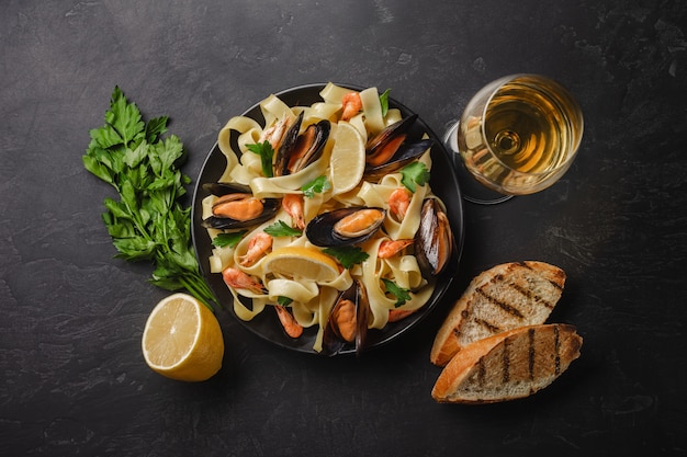 Pasta con frutti di mare e vino bianco sul tavolo di pietra. Cozze e gamberi Vista dall&#39;alto.