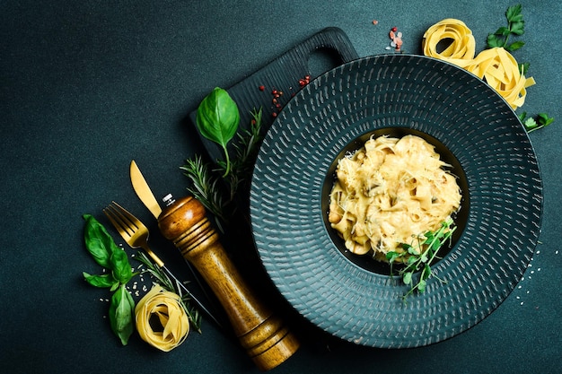 Pasta con funghi e formaggio in una ciotola nera Menu del ristorante Su uno sfondo scuro