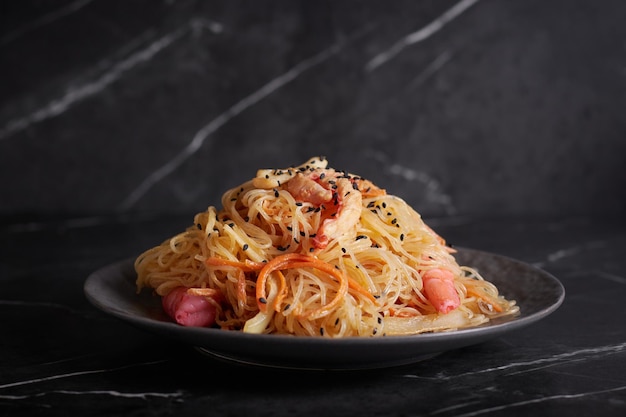 Pasta con gamberi e frutti di mare, spaghetti, tagliatelle, piatto su fondo scuro, cucina asiatica