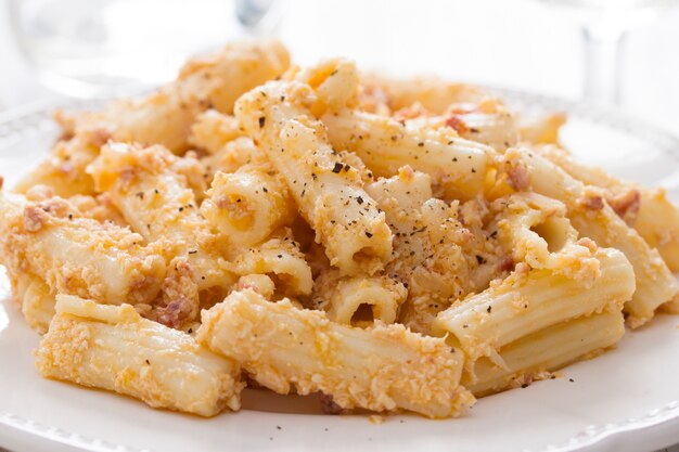 Pasta con il pollo sul piatto bianco su superficie di legno