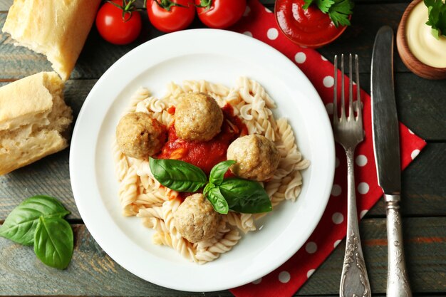 Pasta con le polpette sul piatto sul fondo della tavola di legno