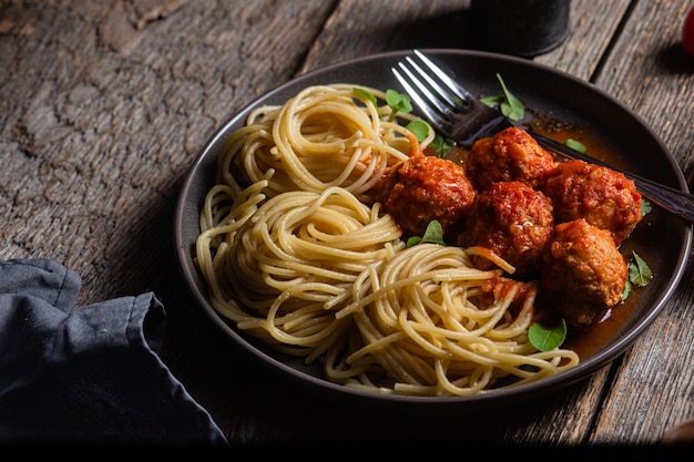 Pasta con polpette e salsa in un piatto su un tavolo di legno