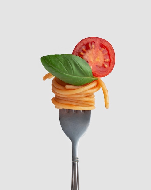 Pasta con pomodori e basilico su una forchetta Sfondo bianco isolato