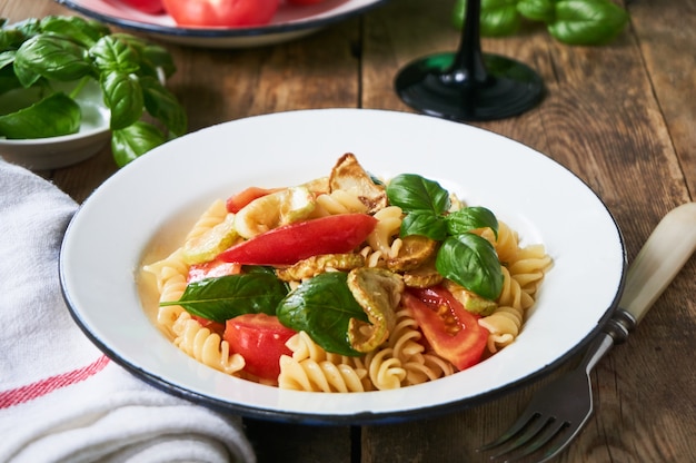 Pasta con pomodori, zucchine e basilico in una ciotola