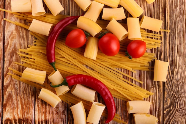 Pasta con pomodorini e altri ingredienti sul tavolo di legno (visto dall'alto)