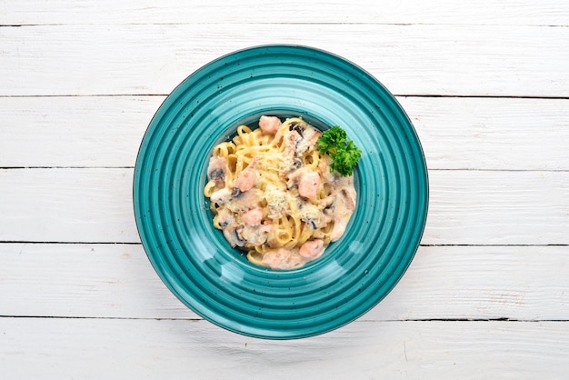 Pasta con salmone e funghi Cucina italiana su sfondo di legno Vista dall'alto Copia spazio