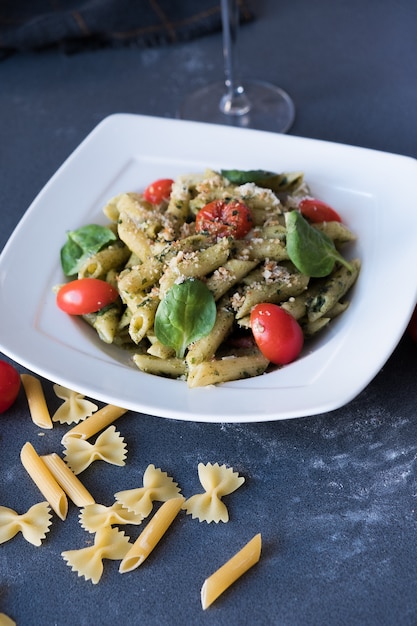 Pasta con salsa di pesto, basilico fresco e noci sul piatto bianco. Spaghetti su sfondo blu scuro