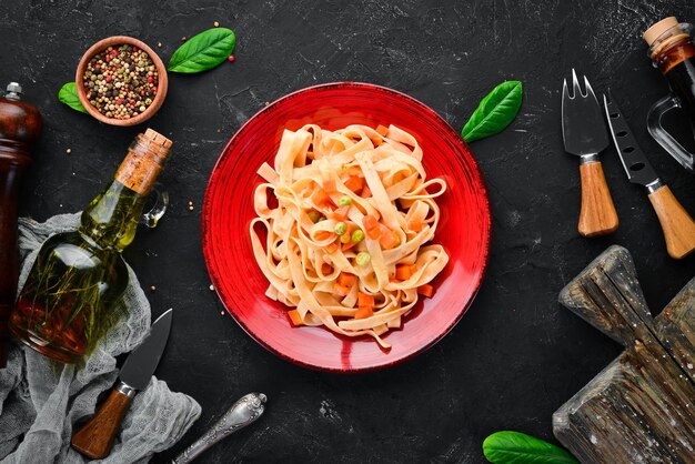 Pasta con verdure e salsa di pomodoro in un piatto Sullo sfondo vecchio Vista dall'alto Spazio libero per il testo