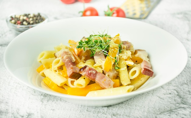 Pasta con zucca e carne decorata con verdure in un piatto bianco Primo piano