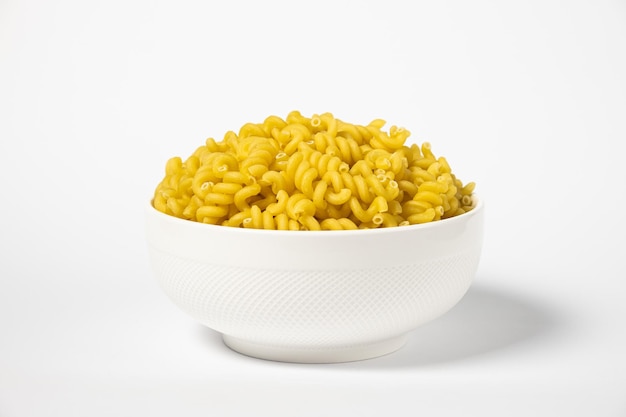 Pasta cruda Cavatappi Cellentani in un piatto isolato su fondo giallo