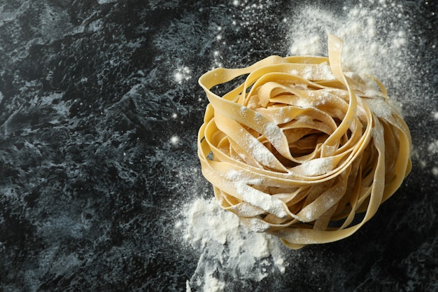 Pasta cruda con farina su sfondo nero smokey