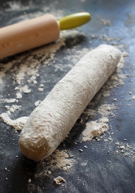 Pasta cruda con un mattarello su un tavolo scuro