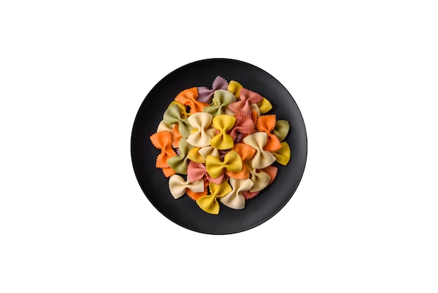 Pasta cruda di farfalle in diversi colori su fondo di cemento scuro Preparazione alla cottura del cibo italiano