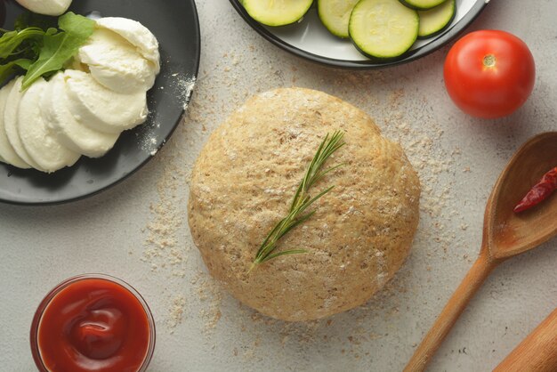 Pasta cruda e ingredienti freschi per pizza vegana.