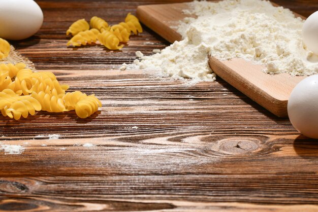 Pasta cruda e ingredienti per la pasta su fondo di legno