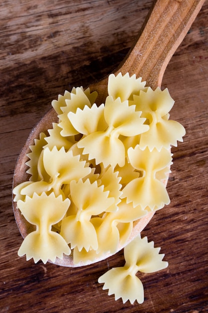 Pasta cruda in primo piano del cucchiaio di legno