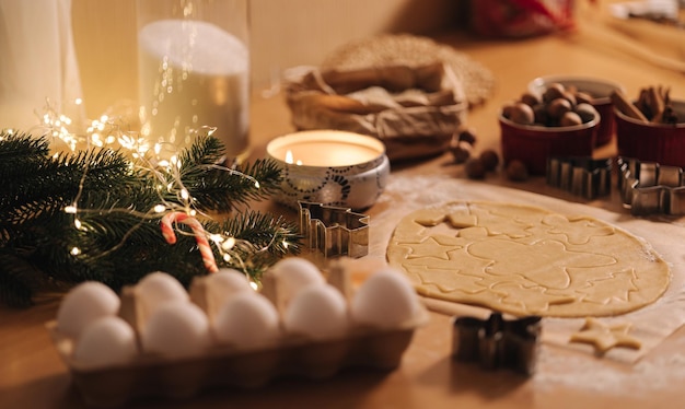 Pasta cruda per la cottura del pan di zenzero dei biscotti di natale sulla luce di candela della tavola di legno alla sera