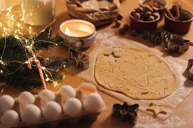 Pasta cruda per la cottura del pan di zenzero dei biscotti di natale sulla luce di candela della tavola di legno alla sera