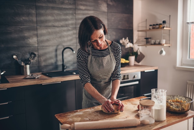 Pasta d'impastamento della donna sulla tavola di legno