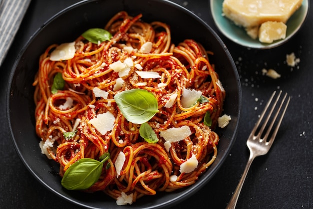 Pasta degli spaghetti con formaggio salsa di pomodoro e basilico servito in una ciotola.