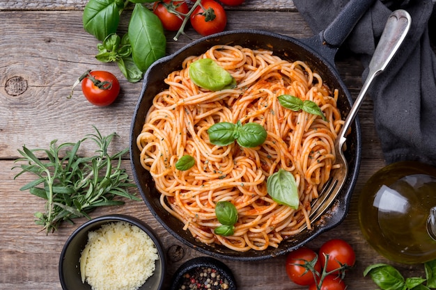 Pasta degli spaghetti con salsa di pomodoro e basilico su legno