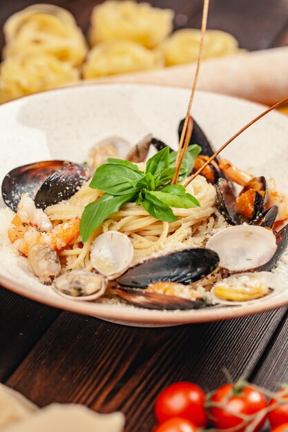 Pasta dei frutti di mare con le cozze e basilico in piatto sulla tavola di legno