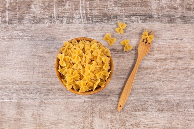 Pasta delle farfalle nella ciotola di legno con la forcella