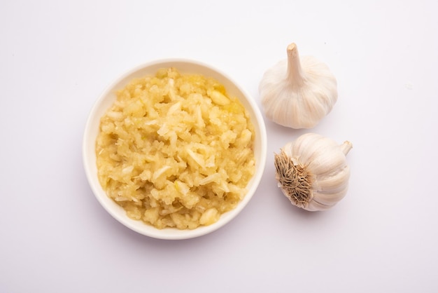 Pasta di aglio o purea di Lahsun con crudo intero, isolato su sfondo bianco. Messa a fuoco selettiva