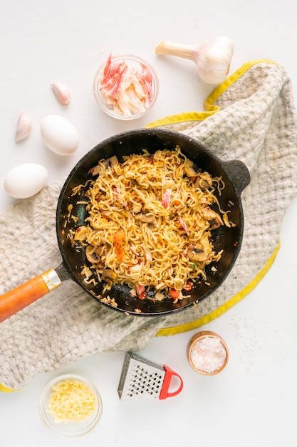 Pasta di carbonaro calda in padella con spezie e ingredienti sul piano del tavolo, ricetta alimentare