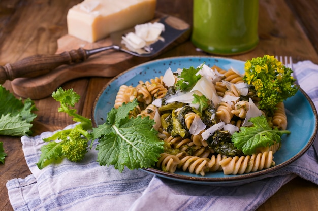 Pasta di Cime di rapa in un piatto sopra con parmigiano su una tavola di legno. Cibo tradizionale del sud Italia, pugliese. Foto in stile rustico. Copia spazio