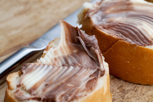 Pasta di cioccolato al cacao naturale durante la colazione, fette di pane bianco con crema di burro dolce al cioccolato, burro morbido al cioccolato e pane bianco