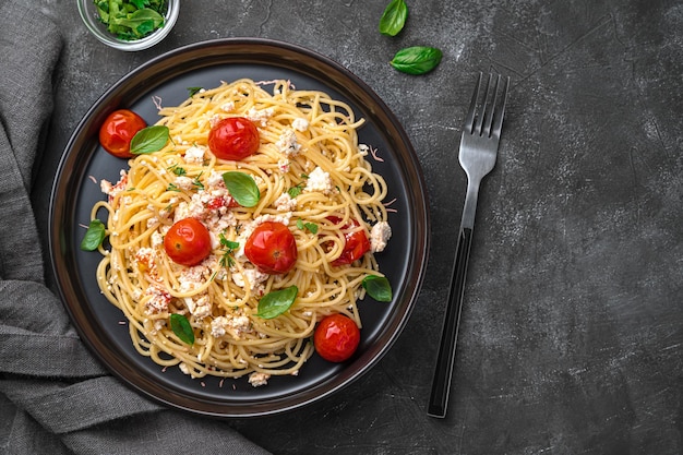 Pasta di feta Pasta popolare con formaggio feta al forno, pomodorini, erbe aromatiche e aglio su sfondo scuro Spazio vista dall'alto da copiare