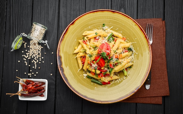 Pasta di penne al pomodoro e pancetta su un tavolo di legno nero