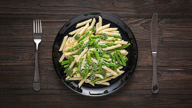 Pasta di penne con fagiolini su un piatto nero