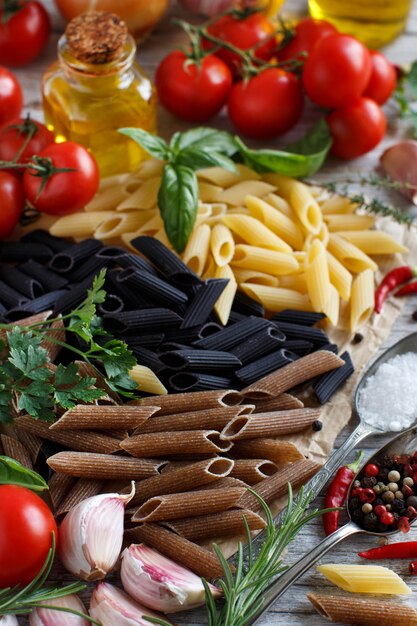 Pasta di penne con verdure, erbe aromatiche e olio d'oliva sulla tavola di legno